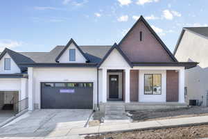 View of front of house with a garage and central AC