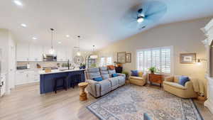 Living room with light wood-type flooring, ceiling fan, and lofted ceiling