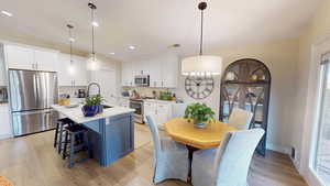 Kitchen featuring appliances with stainless steel finishes, white cabinetry, and hanging light fixtures