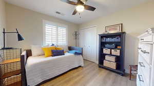 Second bedroom with ceiling fan, light hardwood / wood-style floors, and a closet