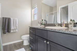 Bathroom with hardwood / wood-style floors, vanity, toilet, and walk in shower