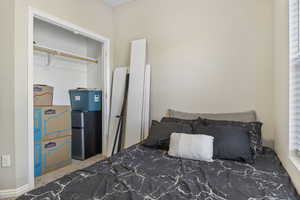 Carpeted bedroom featuring stainless steel fridge and a closet