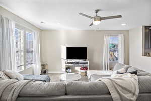 Carpeted living room with a textured ceiling and ceiling fan