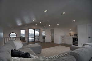 Living room featuring wood-type flooring, wine cooler, lofted ceiling, and sink