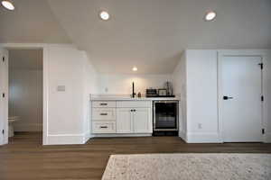 Bar featuring dark hardwood / wood-style flooring, sink, white cabinets, and beverage cooler