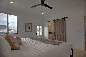 Carpeted bedroom featuring a barn door and ceiling fan