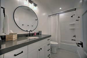 Full bathroom featuring shower / tub combo with curtain, vanity, and toilet