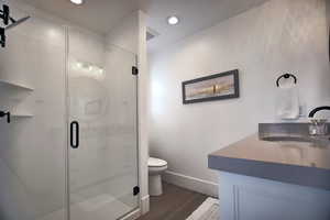 Bathroom featuring walk in shower, hardwood / wood-style floors, vanity, and toilet