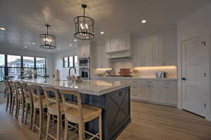 Kitchen featuring an inviting chandelier, a spacious island, hanging light fixtures, appliances with stainless steel finishes, and white cabinetry