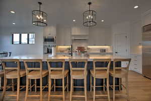 Kitchen featuring appliances with stainless steel finishes, a spacious island, pendant lighting, a notable chandelier, and white cabinetry