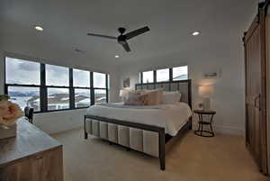 Carpeted bedroom featuring a barn door and ceiling fan