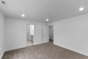 Unfurnished bedroom with light carpet and ensuite bathroom