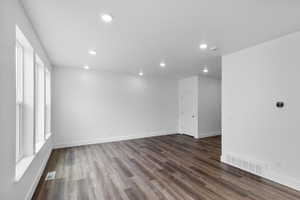 Spare room featuring a healthy amount of sunlight and dark wood-type flooring