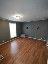 Unfurnished room featuring wood-type flooring and a textured ceiling