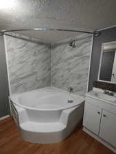 Bathroom featuring vanity, tiled shower / bath combo, a textured ceiling, and hardwood / wood-style flooring