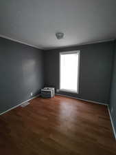 Unfurnished room featuring dark hardwood / wood-style flooring and ornamental molding