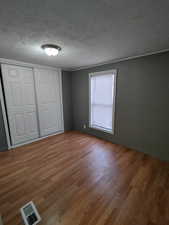 Unfurnished bedroom featuring hardwood / wood-style floors, a textured ceiling, and a closet