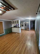 Kitchen with stainless steel fridge with ice dispenser, light hardwood / wood-style flooring, white cabinets, and a textured ceiling