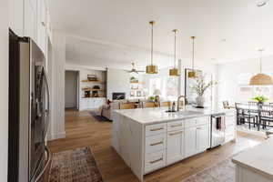 Kitchen featuring stainless steel appliances, ceiling fan, sink, a center island with sink, and white cabinets