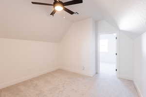 Bonus room with ceiling fan, light colored carpet, and vaulted ceiling