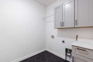 Laundry room featuring electric dryer hookup, hookup for a washing machine, cabinets, and dark tile patterned flooring