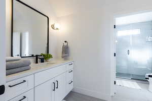 Bathroom featuring vanity, a shower with shower door, and lofted ceiling