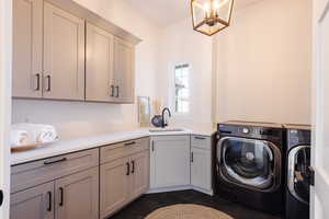 Laundry room featuring dark tile patterned flooring, washer and dryer, cabinets, and sink