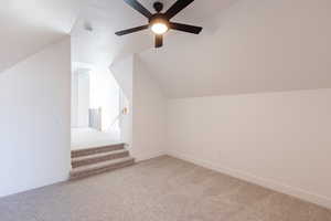 Additional living space with light colored carpet, vaulted ceiling, and ceiling fan