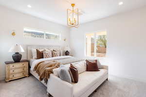 Carpeted bedroom with an inviting chandelier