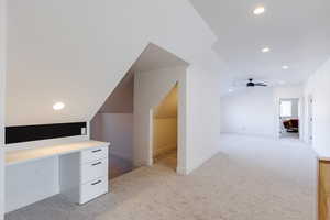 Bonus room featuring ceiling fan, light colored carpet, built in desk, and lofted ceiling