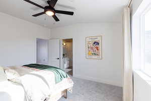 Carpeted bedroom featuring vaulted ceiling, ensuite bath, and ceiling fan