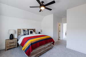 Bedroom featuring light colored carpet, vaulted ceiling, and ceiling fan