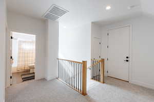 Hallway featuring light carpet and vaulted ceiling