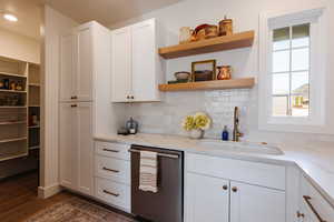 Kitchen featuring light stone countertops, sink, and white cabinets