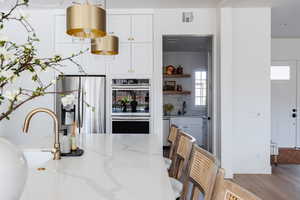 Kitchen with light stone countertops, sink, white cabinetry, backsplash, and appliances with stainless steel finishes