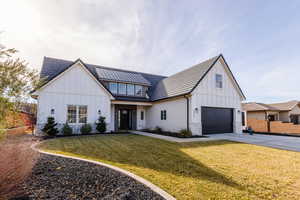 Modern inspired farmhouse with a front lawn and a garage