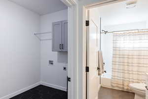 Laundry area featuring hookup for an electric dryer, cabinets, dark tile patterned floors, and washer hookup