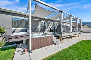 Exterior space featuring a patio, a yard, a hot tub, and a mountain view