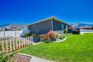 View of side of home with a mountain view and a yard