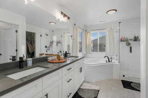 Bathroom with large tub and walk in shower, vanity, and tile patterned floors.