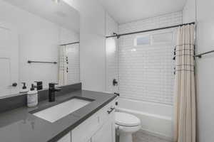 Full bathroom with shower / bath combination, vanity, toilet, and tile patterned floors.