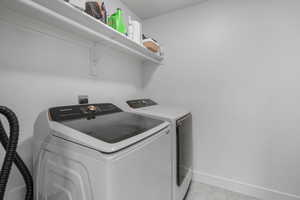 Washroom with separate washer and dryer and light tile patterned floors.