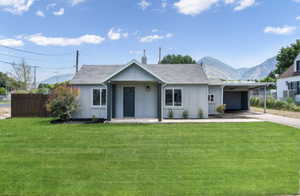 View of front of property with a carport, a mountain view, and a front yard