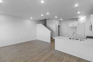 Kitchen featuring kitchen peninsula, light hardwood / wood-style floors, white cabinetry, and sink