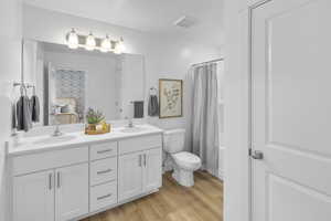 Full bathroom with toilet, shower / bath combo with shower curtain, vanity, and hardwood / wood-style flooring