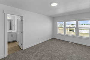 Unfurnished bedroom featuring carpet, connected bathroom, and sink