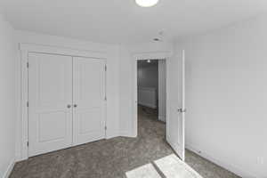 Unfurnished bedroom featuring light carpet and a closet