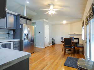 Kitchen with decorative backsplash, stainless steel refrigerator with ice dispenser, vaulted ceiling, and ceiling fan