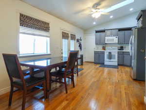 Kitchen with gray cabinetry, white appliances, ceiling fan, light hardwood / wood-style floors, and lofted ceiling