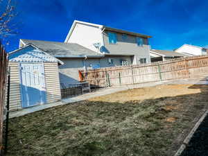 Rear view of property featuring a yard, a storage unit, and a patio area